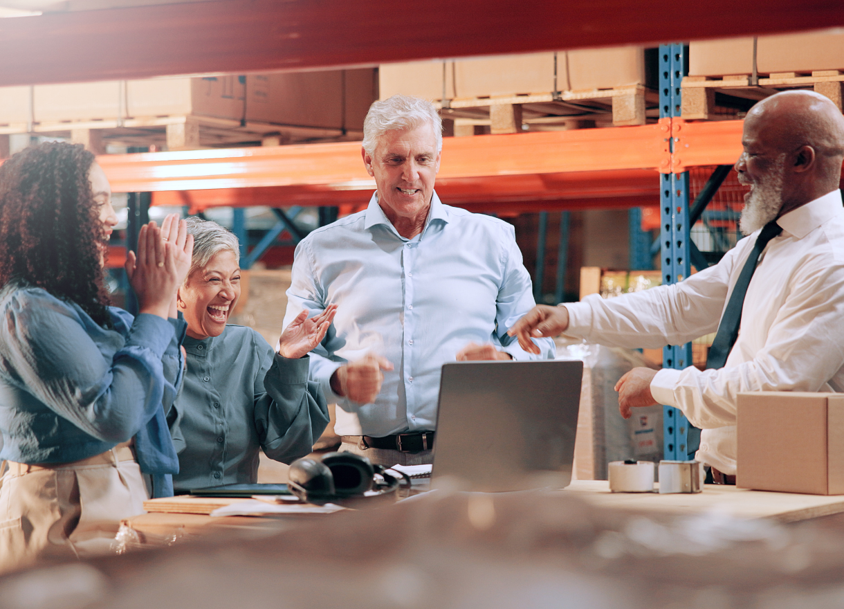 A team celebrating around a laptop in their workplace